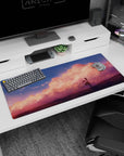 Lone anime girl gazing at the sky on a desk pad 36x16 inches, soft clouds and tiny sparks.