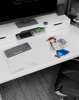 32x16 inches mouse pad showing glossy-eyed anime girl waving, chestnut twin-tails, floral blouse, navy skirt.