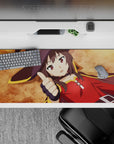 Anime desk pad 36x16 inches featuring Megumin from KonoSuba, lying down with a thumbs up, vibrant ochre background.
