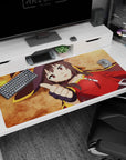 Megumin from KonoSuba on a 40x20 inch anime desk pad, showcasing her signature witch hat and crimson cloak on an ochre background.