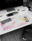 36x16 inches Sailor Moon desk pad, arm raised as petals drift by, red bow and navy pleats against cotton-candy clouds.