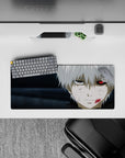 Anime mouse pad 28x12 inches featuring a character with one glowing red eye, set against muted grays, exuding a haunting vibe.