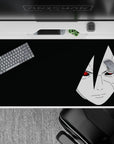 Dark black desk pad 40x20 inches with pale portrait and red Sharingan eyes, moody midnight vibe.