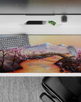 36x16 inches desk pad with cherry blossom landscape, capturing the tranquility of snow-capped mountains and delicate blossoms along a serene river.