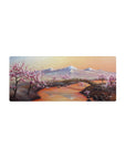 Mouse pad featuring cherry blossom landscape, 28x12 inches, with snow-capped mountains, a serene river, and pink blossoms for a calming, natural aesthetic.