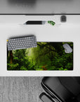 Peaceful 28x12 mouse pad with moss-covered trees, ferns, and vines, creating a tranquil atmosphere and nature-filled workspace