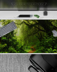 Lush 40x20 desk pad with moss-covered trees, ferns, and vines, capturing the beauty of the rainforest for a tranquil, nature-inspired workspace