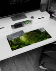 Lush 28x12 mouse pad featuring soft light filtering through mist, moss-covered trees, and ferns for a calming desk environment