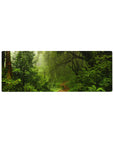 Rainforest 32x12 mouse pad with moss-covered trees, ferns, vines, and soft light filtering through mist for a peaceful desk environment