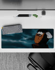 32x12 inches anime mouse pad in dark blacks with warm orange mask tones and moody blue-gray cloud swirls.