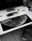 Cratered full moon floating in star-speckled space desk pad 36x16 inches, minimalist sci-fi look.