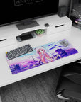 32x12 inches desk mat featuring shy pink-haired anime girl in cat-ear hoodie waving over city rooftops.