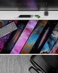 Cosmic gradient desk pad 40x20 inches in purple, electric blue, pink, and smoky black tones.