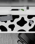 Whimsical 36x16 desk pad with bold black and white cow print spots, perfect for bringing creativity and fun into your workspace