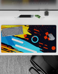 Impactful 32x16 desk mat combines yellow, orange, and blue tones with geometric precision for stylish yet inspiring visuals