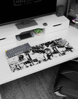 Wide-eyed chibi anime girls with sleepy smiles across a black-and-white desk mat mouse pad 32x12 inches.