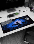 Artistic 36x16 inches desk pad featuring Guts in his Berserker Armor surrounded by jagged shadows and glowing blue light, perfect for adding tense energy to your desk setup.