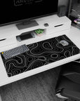 Artistic 36x16 inches desk pad featuring black and white topographic contours, with sharp lines and dotted patterns adding a modern, graphic touch.