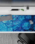 Calming 36x16 desk pad with dynamic oceanic blues and bubble-like details, creating a serene and visually engaging experience