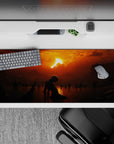 36x16 inches desk pad showcasing a solitary figure kneeling under a fiery sunset, surrounded by dark shadows, perfect for fans of dark, moody landscapes.