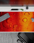 Dynamic 40x20 desk pad showcases liquid-like abstract bubbles with warm, vibrant tones for an inspiring workspace vibe