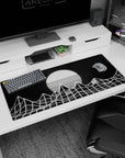 Artistic 36x16 inches desk pad with minimalist wireframe mountains and a glowing striped sun in monochrome vaporwave style.