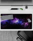 Cosmic desk mouse pad 32x16 inches featuring black nebula clouds, violet haze, and soft blue stardust design.