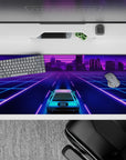 36x16 inches desk pad with a neon car cruising through a glowing city, set against vibrant colors and a retro-futuristic grid.