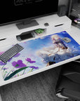 Blonde anime girl in billowing white skirts under a soft breeze, floral sparkles desk pad 40x20 inches.