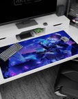 Golden-haired anime heroine lounging with smirk, raised hand and floating green charm desk pad 40x20 inches.
