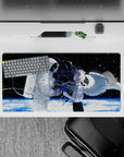 Moody black space anime mouse pad 32x16 inches with icy planet glow and blue paint-splash accents.