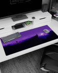 Calming 36x16 anime desk mat with a moonlit wilderness in purple tones, silhouetted mountains, and trees under a starry sky for a serene vibe