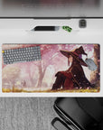 Megumin from Konosuba on 32x16 inch anime mouse pad, under sakura trees, creating a serene and magical desk atmosphere.