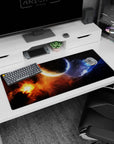 Cratered planet scene desk pad 36x16 inches with orange nebula burst and drifting blue haze on black.