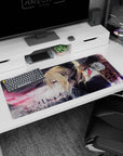 36x16 inches Violet Evergarden desk pad with wind-swept hair, sharp blue eye, and embers over a gray sky.