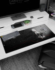 36x16 inches NieR:Automata 2B desk pad, standing still holding a soft bunny as black petals fall.