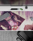 Nezuko from Demon Slayer lounges under wisteria on a 40x20 inch anime desk pad, surrounded by blush-pink blooms.