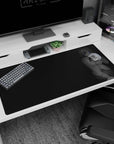 Shy smiling anime girl in headphones on desk pad 40x20 inches, soft grayscale art with skirt folds.
