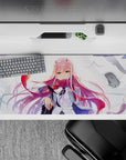 Powerful 36x16 desk pad with Zero Two’s fierce emerald eyes, flowing pink hair, and dynamic windswept background
