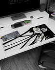 Close-up anime girl with ink-black hair ribbons and sweet blush over floral pattern desk pad, 36x16 inches.
