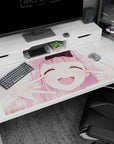 Anime girl desk pad 40x20 inches showing pink-haired girl with black bow, cheeks squished into grin.