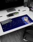 Blonde anime girl in oversized blue hoodie looking aside on 36x16 inches desk pad with firefly specks.