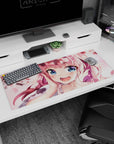 Close-up pink-haired anime girl with heart highlights and drifting sakura petals desk pad 36x16 inches.