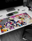 Honoka and friends in sparkly group hug with tiny hats and frills on desk pad, 40x20 inches.