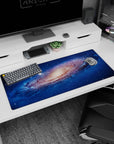 Space vortex scene desk pad 36x16 inches featuring a swirling galaxy center and scattered starlight.