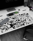 Swirling pile of skull-masked faces and hollow eyes anime desk pad 40x20 inches in stark ink.