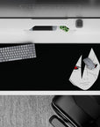 Dark black anime desk pad 36x16 inches with pale portrait and red Sharingan eyes, midnight mood.