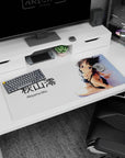 36x16 inches Akiyama Mio desk pad, seated in black bikini with over-the-shoulder shy glance and ribboned hair.