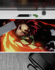 Tanjiro wielding fiery blade mid-swing on 40x20 inch anime mouse pad with reds, golds, and embers against a black backdrop.