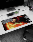 Tanjiro from Demon Slayer wielding a fiery sword on a 32x16 inch anime mouse pad, vivid reds and golds against a black backdrop.